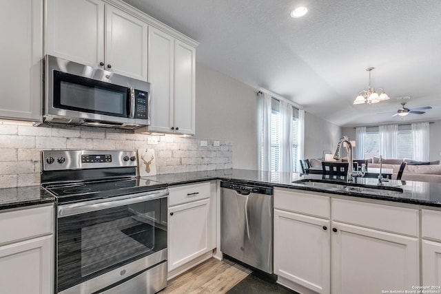 kitchen with white cabinetry, sink, dark stone countertops, ceiling fan with notable chandelier, and appliances with stainless steel finishes