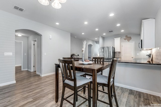 dining space featuring lofted ceiling and light hardwood / wood-style flooring