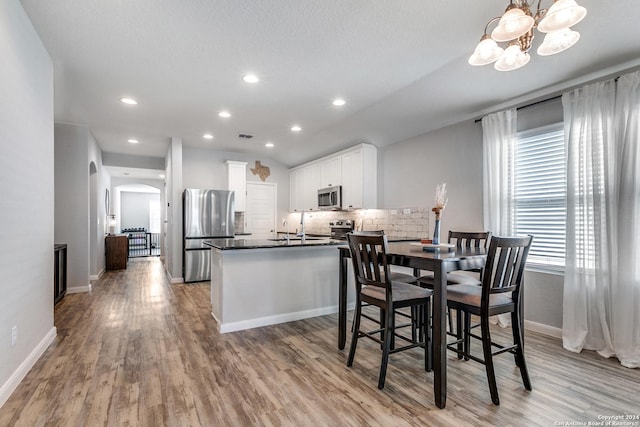 dining room featuring a chandelier, a textured ceiling, light wood-type flooring, and sink