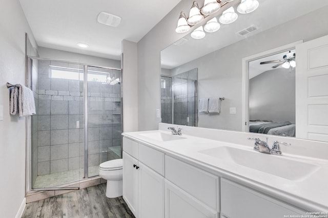 bathroom featuring ceiling fan, hardwood / wood-style floors, toilet, vanity, and a shower with shower door