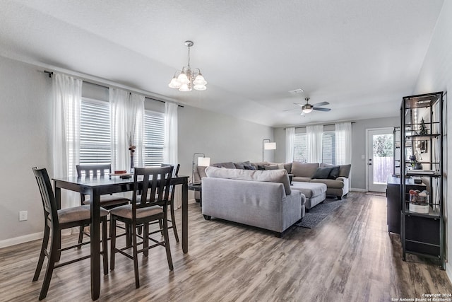 dining room with hardwood / wood-style floors, ceiling fan with notable chandelier, and a textured ceiling