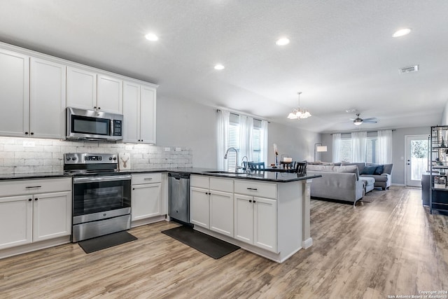 kitchen featuring white cabinets, plenty of natural light, stainless steel appliances, and ceiling fan with notable chandelier