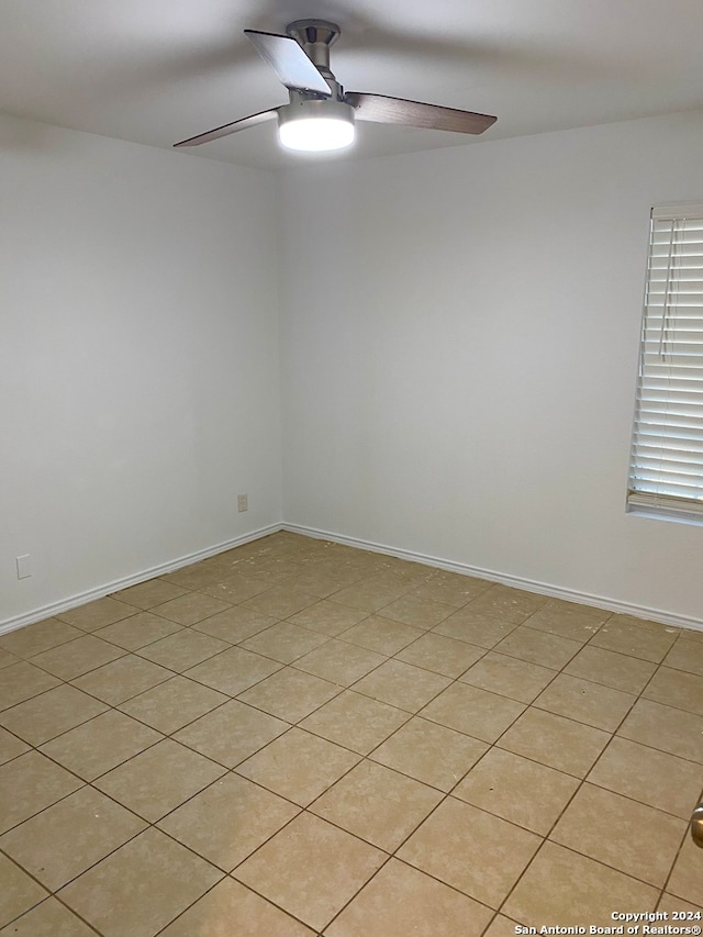 tiled spare room with ceiling fan