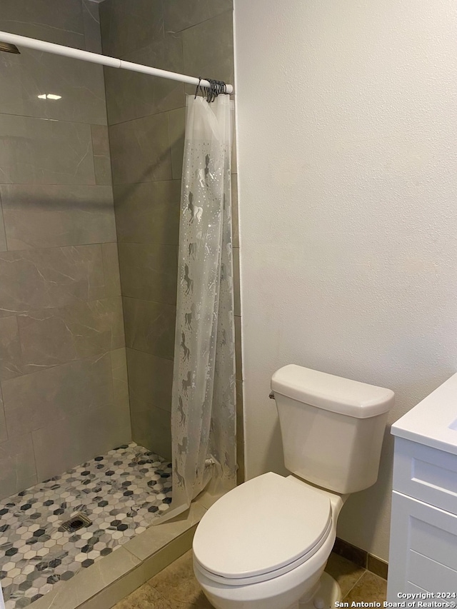 bathroom featuring tile patterned flooring, vanity, toilet, and walk in shower