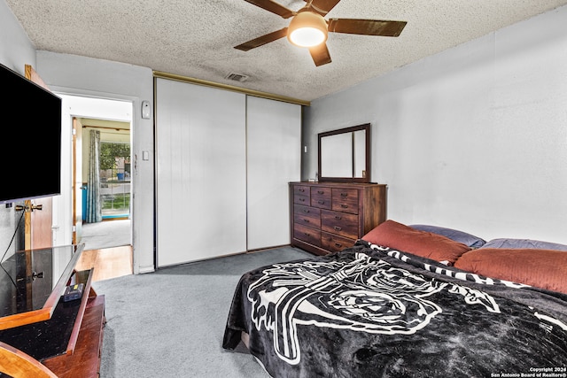 carpeted bedroom with ceiling fan, a textured ceiling, and a closet