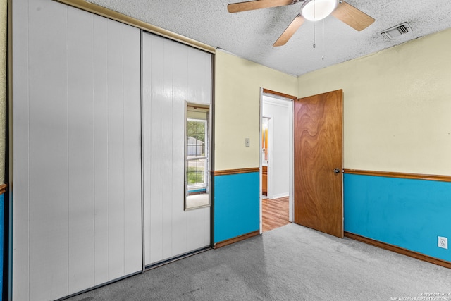 unfurnished bedroom featuring carpet flooring, a textured ceiling, and ceiling fan