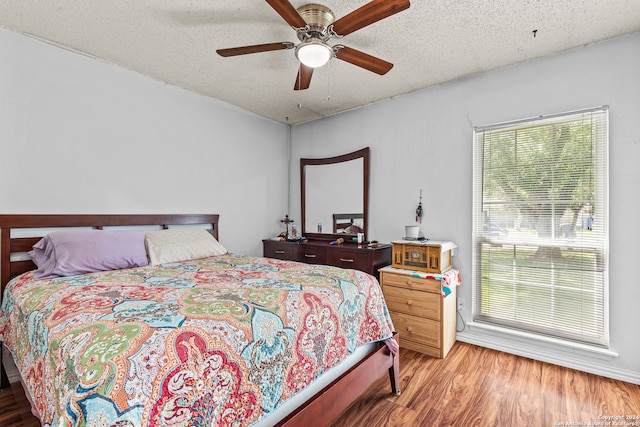 bedroom featuring hardwood / wood-style floors, a textured ceiling, and ceiling fan