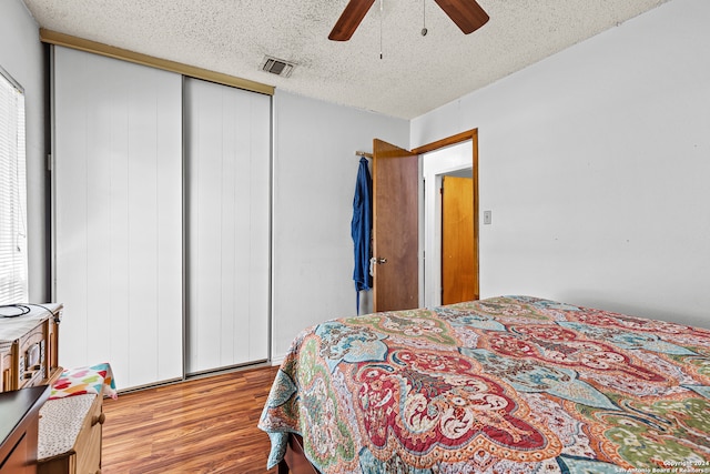 bedroom featuring ceiling fan, light hardwood / wood-style floors, a textured ceiling, and a closet