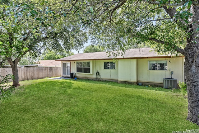 rear view of property featuring a lawn and cooling unit