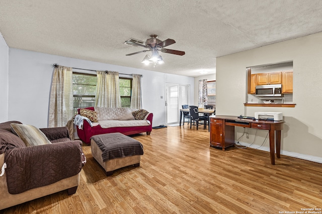 living room featuring a textured ceiling, light wood-type flooring, and ceiling fan