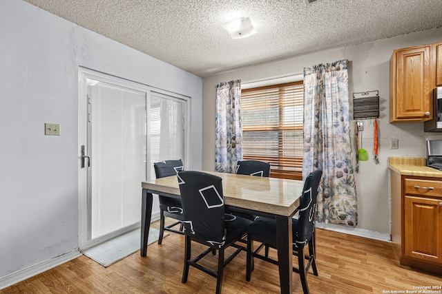 dining space featuring a textured ceiling and light hardwood / wood-style flooring