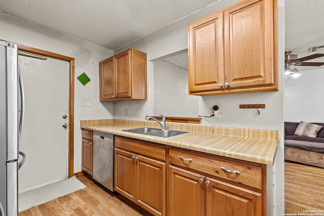 kitchen with sink, light hardwood / wood-style floors, a textured ceiling, and appliances with stainless steel finishes