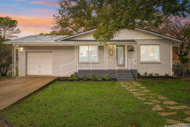 view of front of property with brick siding, a porch, driveway, a yard, and an attached garage