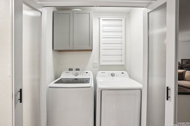 clothes washing area featuring washer and clothes dryer and cabinets