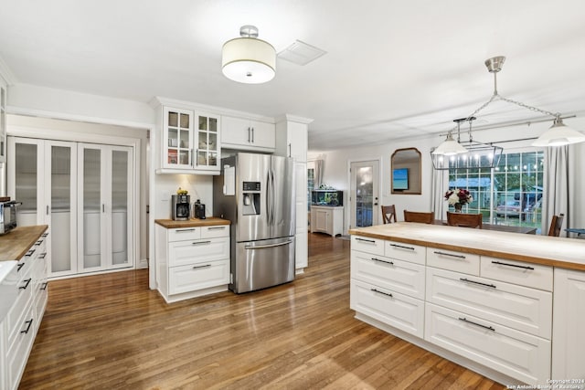 kitchen with white cabinetry, wood counters, light hardwood / wood-style flooring, stainless steel fridge, and pendant lighting