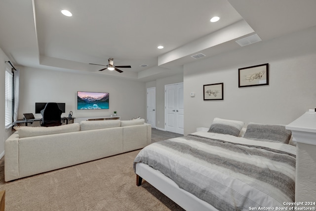 carpeted bedroom featuring a tray ceiling and ceiling fan