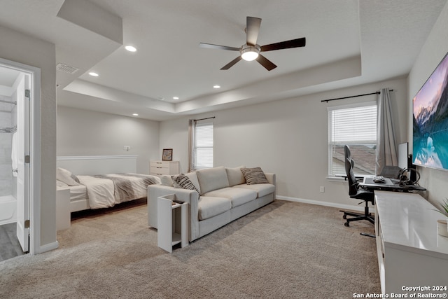 bedroom featuring light carpet, a tray ceiling, and multiple windows