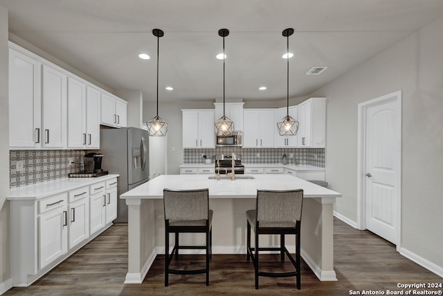 kitchen featuring white cabinets, pendant lighting, a center island with sink, and appliances with stainless steel finishes