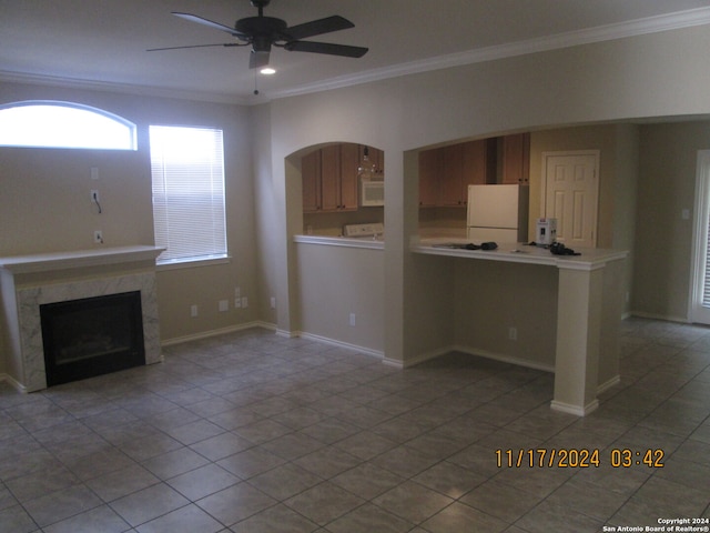 unfurnished living room featuring ceiling fan, a high end fireplace, light tile patterned flooring, and ornamental molding