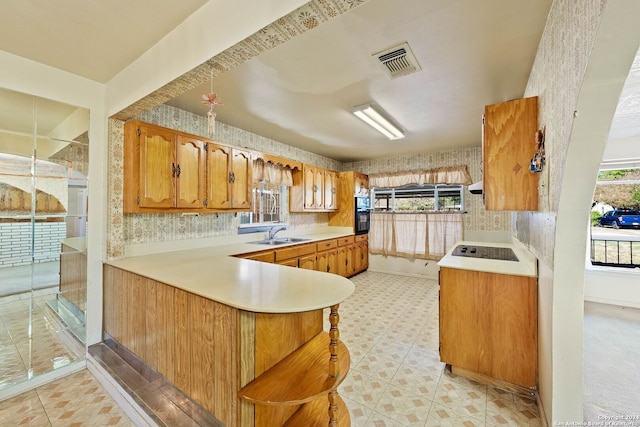 kitchen with black appliances, kitchen peninsula, sink, and a healthy amount of sunlight