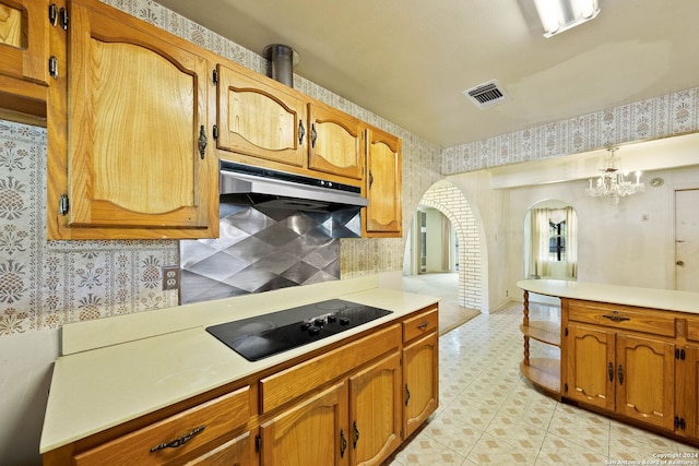 kitchen featuring backsplash, hanging light fixtures, black electric stovetop, and a chandelier