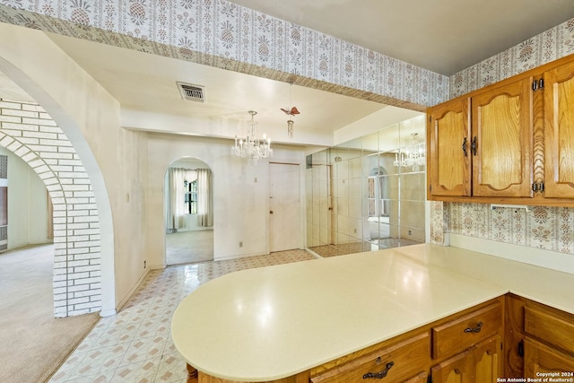 kitchen with a notable chandelier, kitchen peninsula, hanging light fixtures, and light carpet