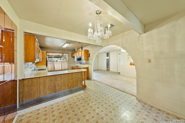 kitchen featuring beamed ceiling, light colored carpet, decorative light fixtures, and a notable chandelier