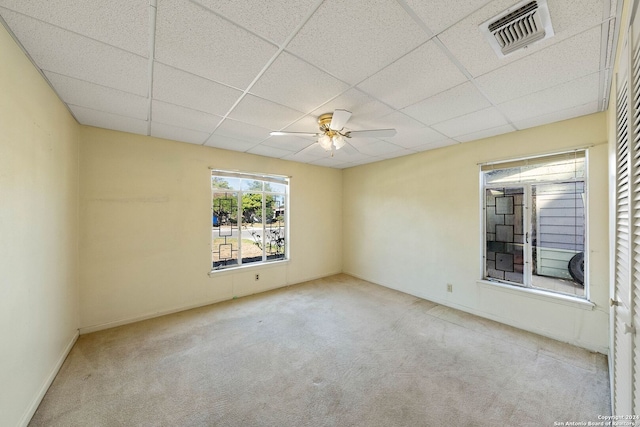 unfurnished room with a paneled ceiling, ceiling fan, and light carpet