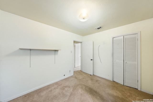 unfurnished bedroom featuring light carpet and a closet