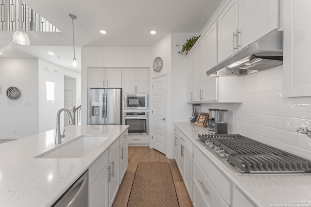 kitchen featuring stainless steel appliances, sink, pendant lighting, light hardwood / wood-style flooring, and white cabinetry