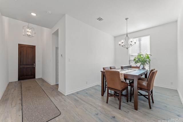 dining room with light wood-type flooring and a notable chandelier