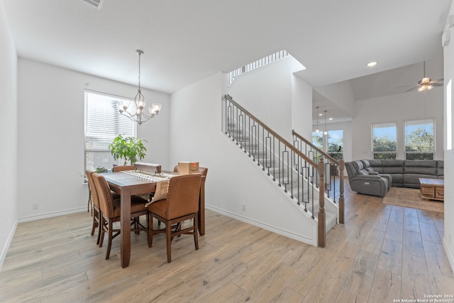 dining space with ceiling fan with notable chandelier and light wood-type flooring