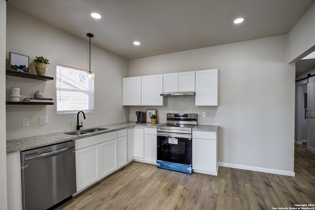 kitchen with white cabinets, sink, a barn door, light wood-type flooring, and appliances with stainless steel finishes