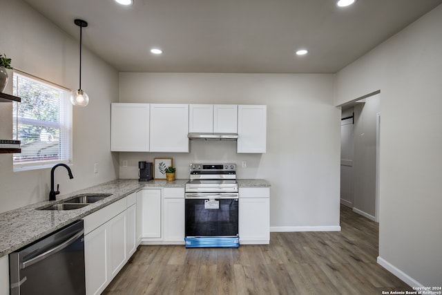 kitchen with appliances with stainless steel finishes, light wood-type flooring, sink, pendant lighting, and white cabinetry