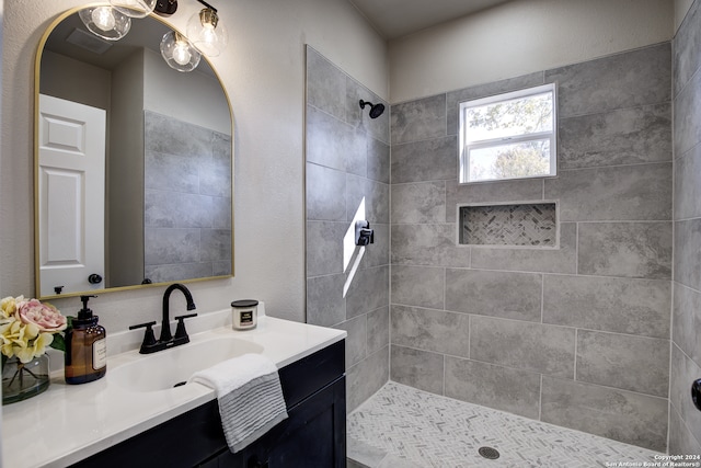 bathroom with a tile shower and vanity