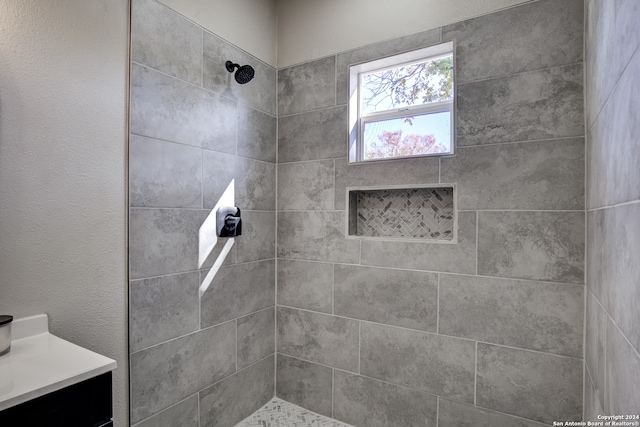 bathroom with a tile shower and vanity