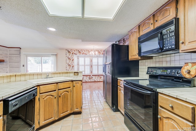 kitchen with tile countertops, sink, black appliances, and a textured ceiling