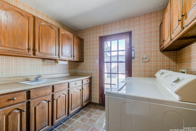 laundry area featuring washing machine and dryer, sink, cabinets, and a textured ceiling