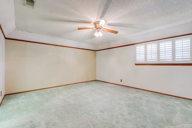 empty room with light carpet, a textured ceiling, ceiling fan, and ornamental molding