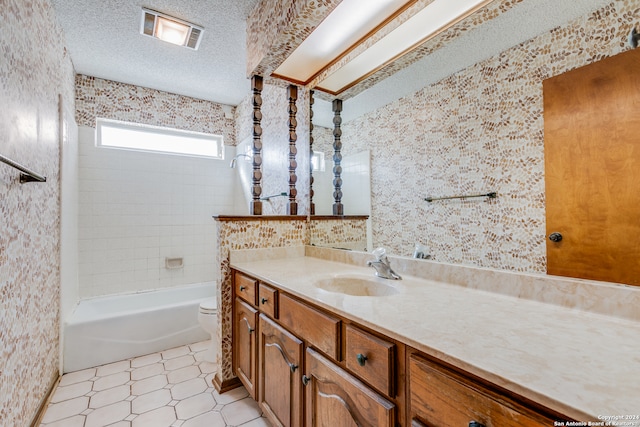 full bathroom with vanity, a textured ceiling, toilet, and tiled shower / bath