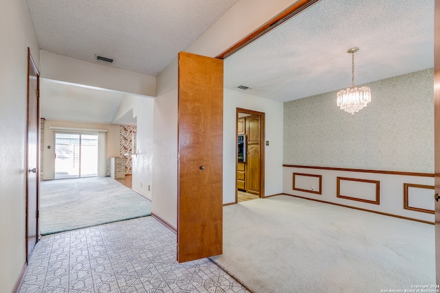 unfurnished room with light carpet, a textured ceiling, vaulted ceiling, and a notable chandelier