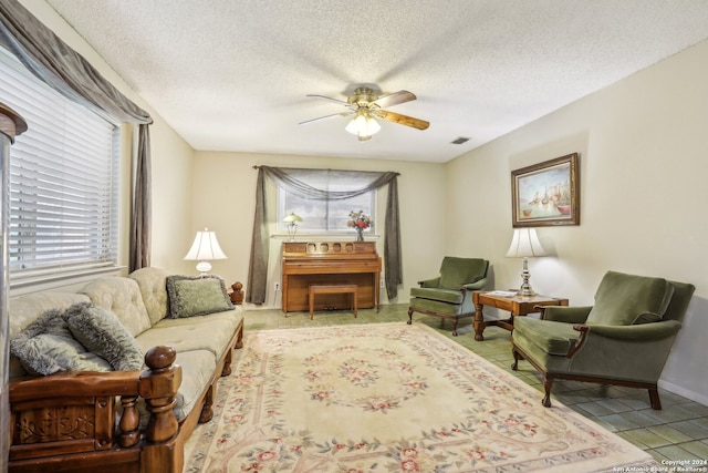 tiled living room with ceiling fan and a textured ceiling