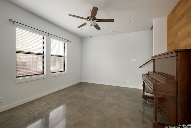 spare room featuring ceiling fan and wood walls