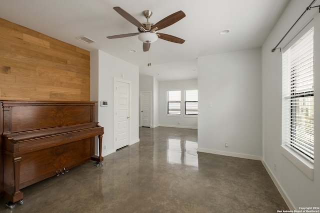 misc room with ceiling fan and wood walls