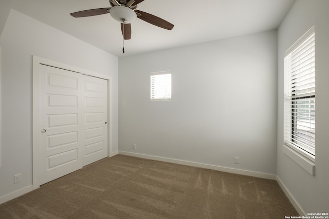 unfurnished bedroom featuring carpet flooring, multiple windows, ceiling fan, and a closet