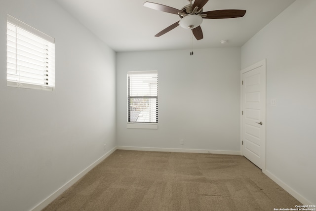 carpeted spare room featuring ceiling fan