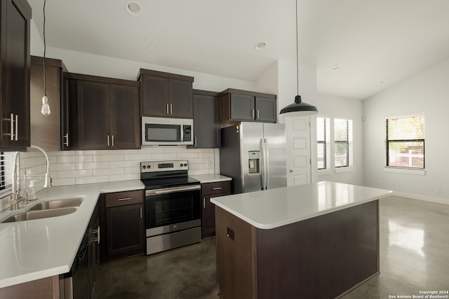 kitchen featuring sink, vaulted ceiling, appliances with stainless steel finishes, decorative light fixtures, and a kitchen island