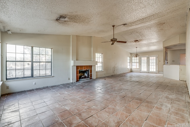 unfurnished living room with a textured ceiling, ceiling fan, light tile patterned floors, a fireplace, and lofted ceiling