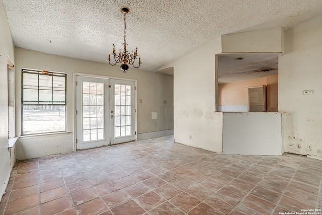 spare room with an inviting chandelier, a textured ceiling, and french doors