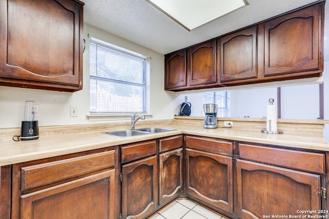 kitchen featuring sink, light tile patterned floors, and a textured ceiling